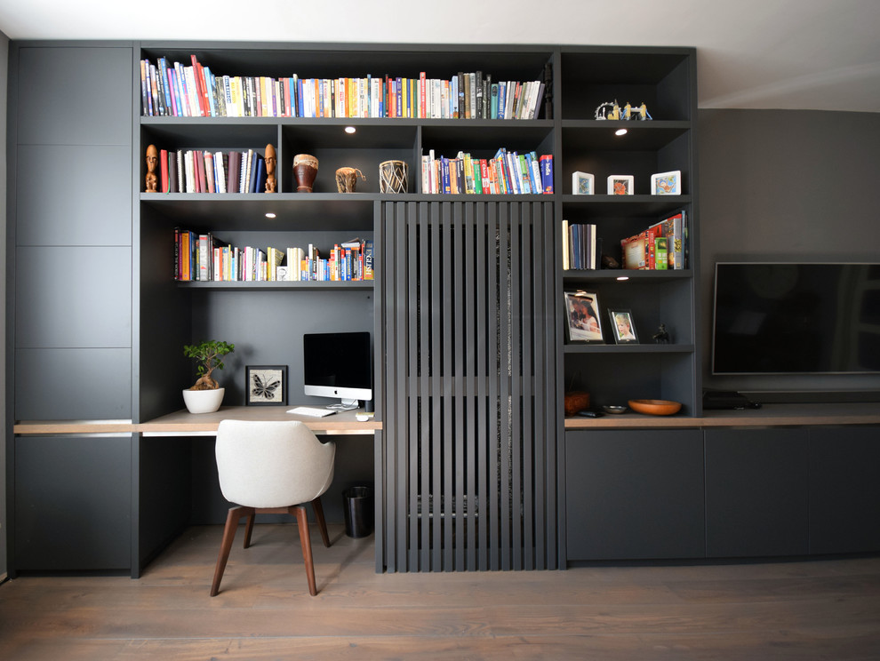 Cette image montre un petit salon minimaliste avec un mur gris, parquet clair, aucune cheminée et un téléviseur fixé au mur.