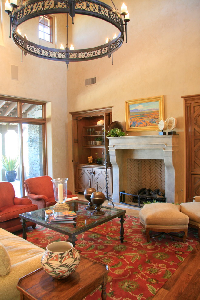 Example of a large tuscan medium tone wood floor living room design in Phoenix with beige walls, a standard fireplace, a stone fireplace and a concealed tv