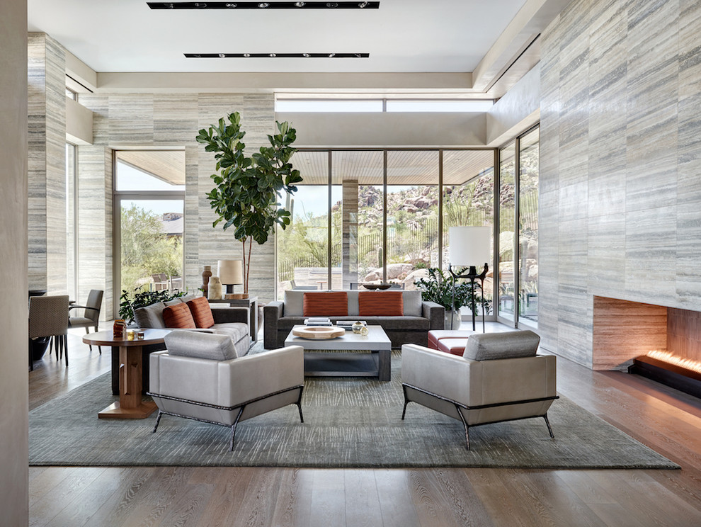 Design ideas for an expansive modern formal open plan living room in Phoenix with grey walls, medium hardwood flooring, a standard fireplace, a stone fireplace surround and feature lighting.
