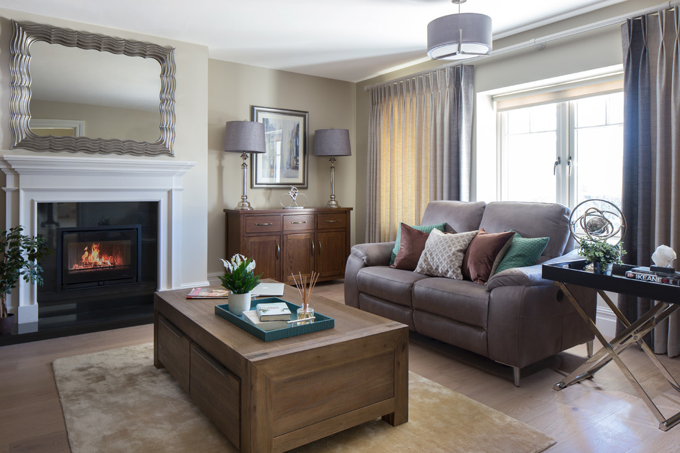 ダブリンにある中くらいなトランジショナルスタイルのおしゃれなリビング (ベージュの壁、淡色無垢フローリング、標準型暖炉、石材の暖炉まわり、茶色い床、茶色いソファ) の写真