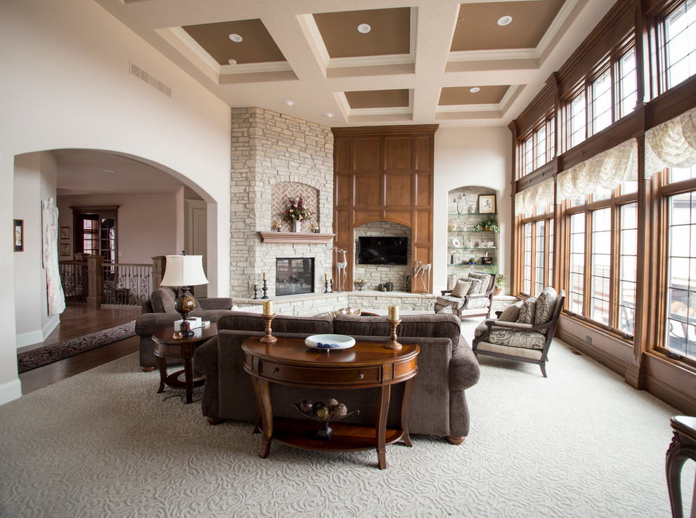 Стильный дизайн: большая открытая гостиная комната в классическом стиле с бежевыми стенами, ковровым покрытием, угловым камином, фасадом камина из камня и телевизором на стене - последний тренд