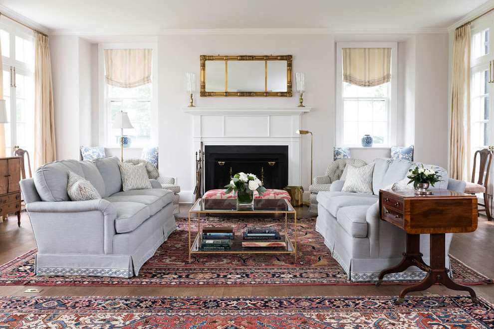 Immagine di un soggiorno classico con pareti bianche, pavimento in legno massello medio, camino classico e pavimento marrone