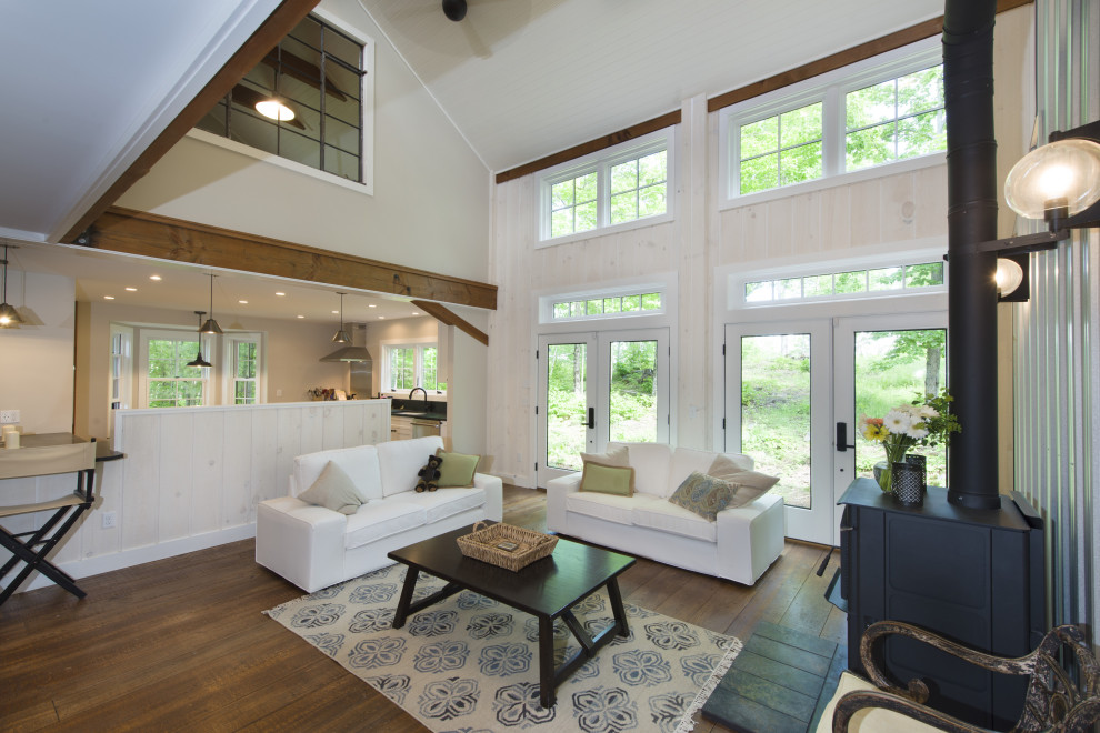Ejemplo de salón abierto de estilo de casa de campo con paredes blancas, suelo de madera en tonos medios, estufa de leña, marco de chimenea de metal y suelo marrón