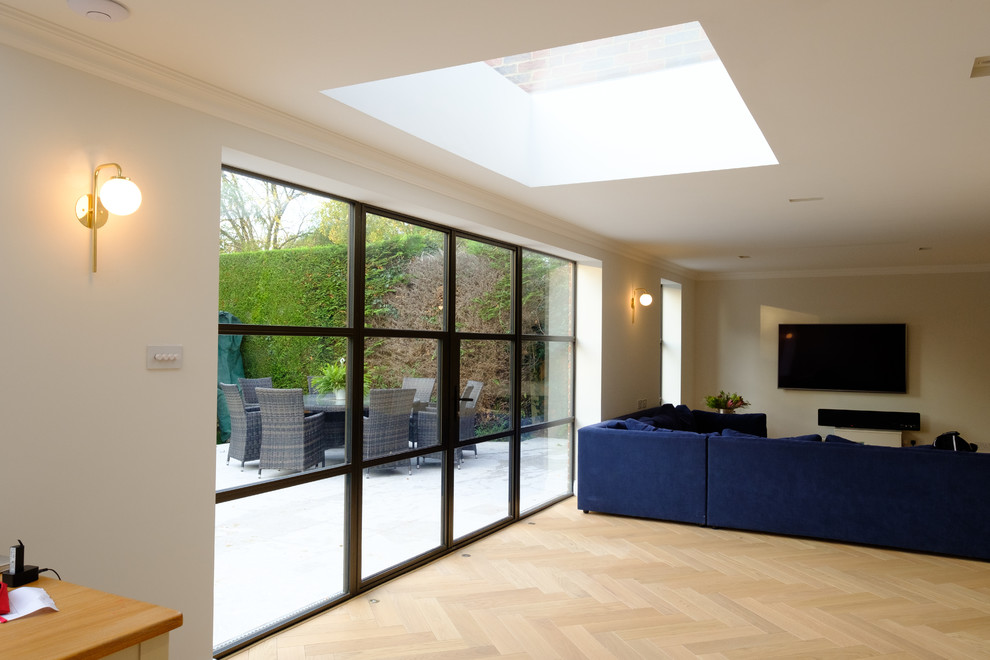 Offenes Modernes Wohnzimmer mit weißer Wandfarbe, braunem Boden und TV-Wand in Buckinghamshire