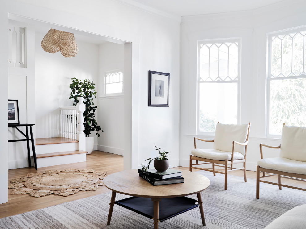 Photo of a medium sized scandinavian formal enclosed living room in San Francisco with white walls, medium hardwood flooring, a corner fireplace, a tiled fireplace surround, no tv and brown floors.