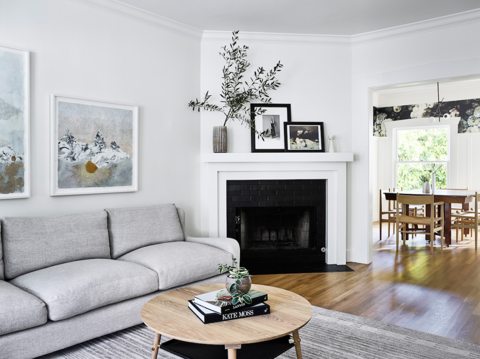 Design ideas for a medium sized scandinavian formal enclosed living room in San Francisco with white walls, medium hardwood flooring, a corner fireplace, a tiled fireplace surround, no tv and brown floors.
