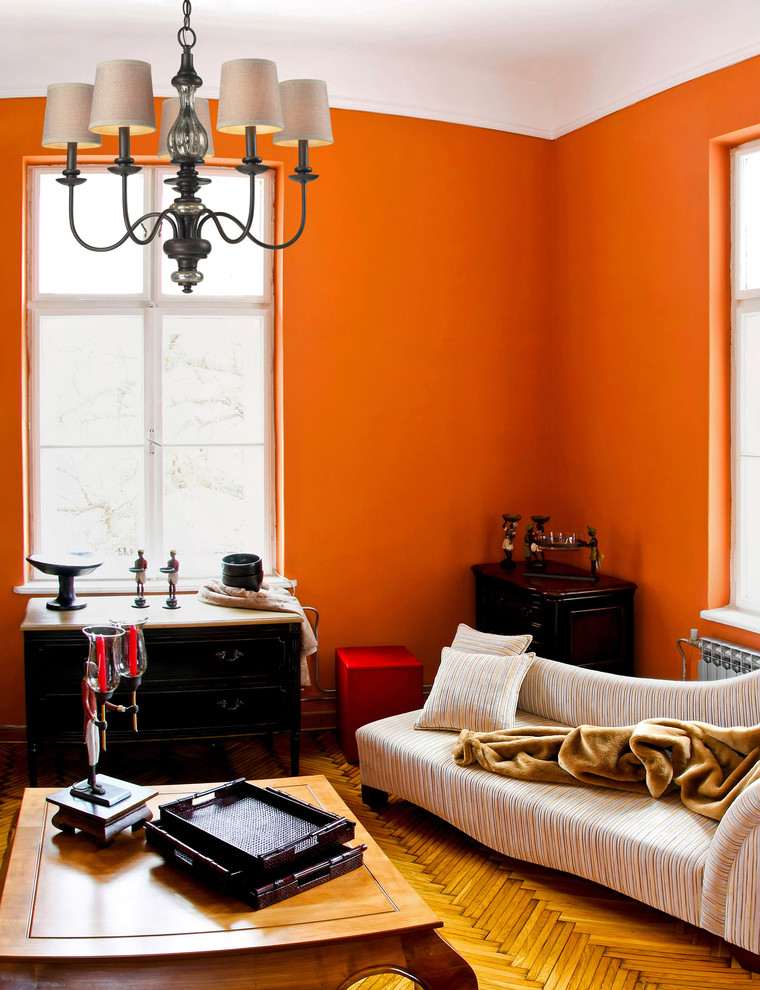 Idée de décoration pour un grand salon tradition fermé avec une salle de réception, un mur orange, un sol en bois brun, aucune cheminée, un manteau de cheminée en pierre et un téléviseur fixé au mur.
