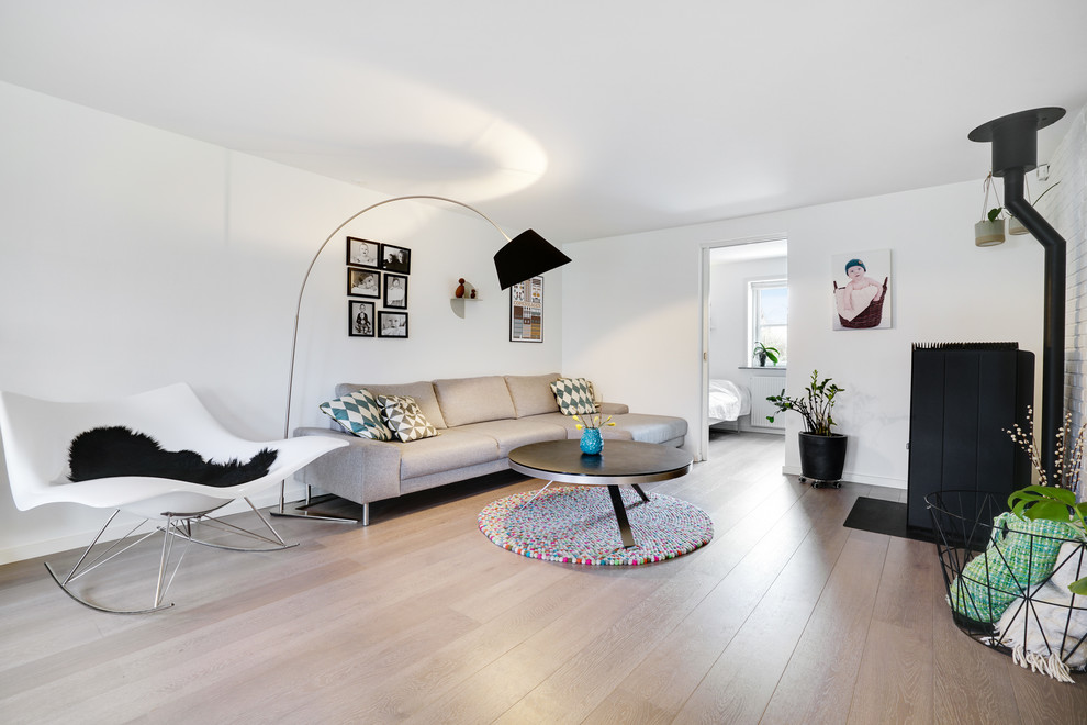 Esempio di un soggiorno scandinavo di medie dimensioni con pareti bianche, pavimento in laminato, stufa a legna, sala formale, cornice del camino in metallo e pavimento beige