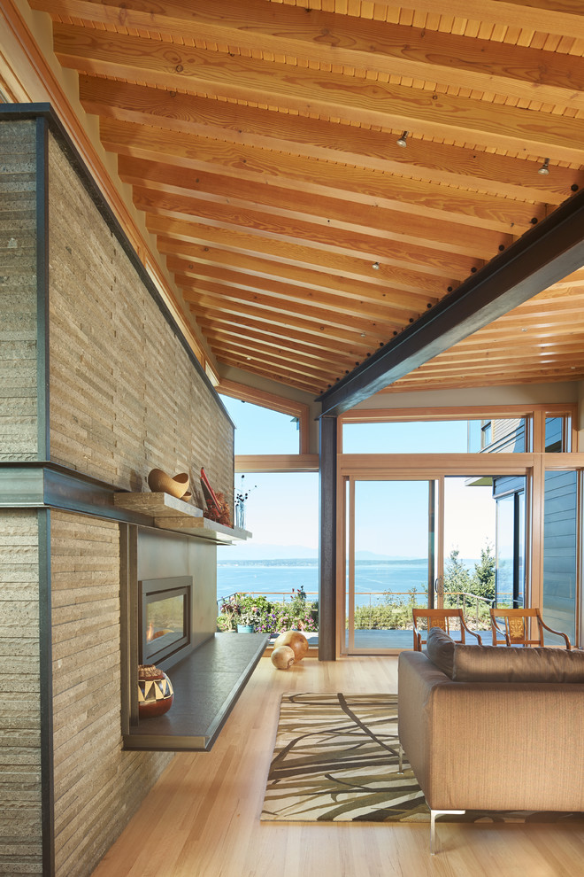 Mittelgroßes Modernes Wohnzimmer mit hellem Holzboden, Kamin und Kaminumrandung aus Stein in Seattle