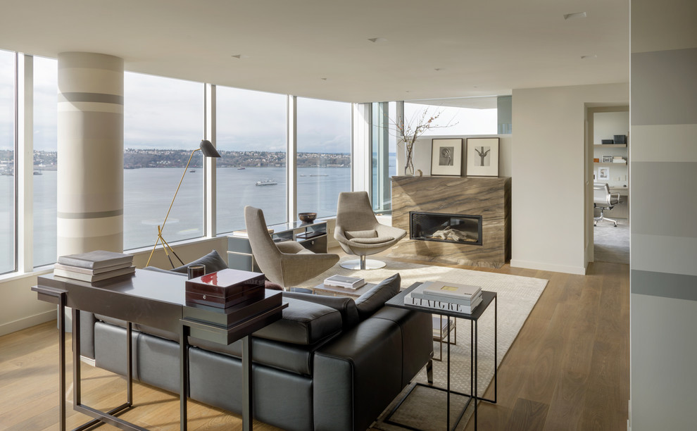 This is an example of a modern living room in Seattle with white walls, medium hardwood flooring, a ribbon fireplace, a stone fireplace surround and brown floors.