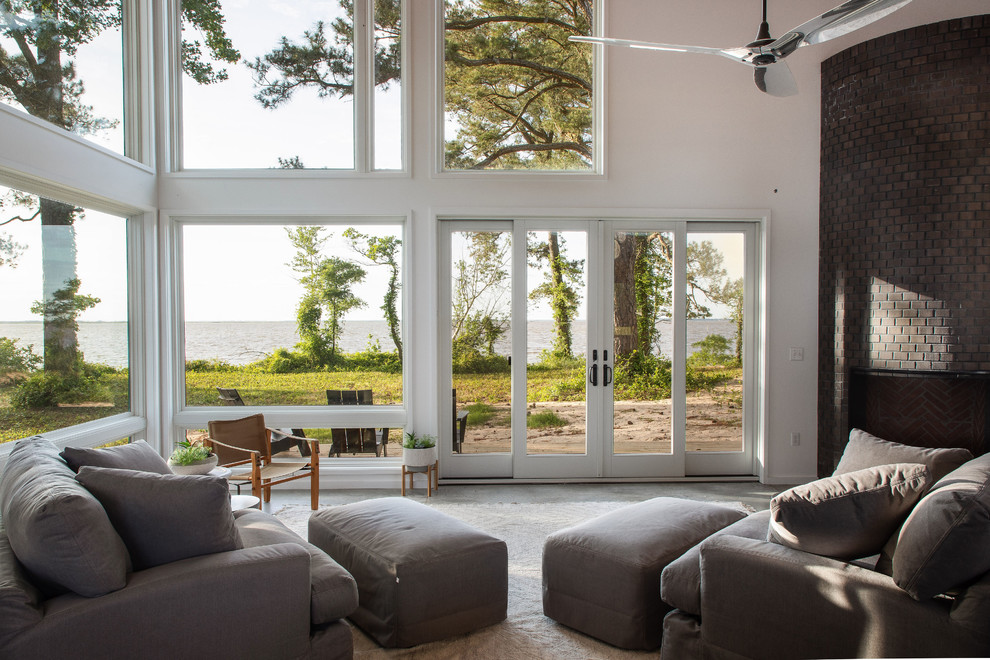 Immagine di un piccolo soggiorno design aperto con pareti bianche, pavimento in cemento, cornice del camino in mattoni e pavimento grigio