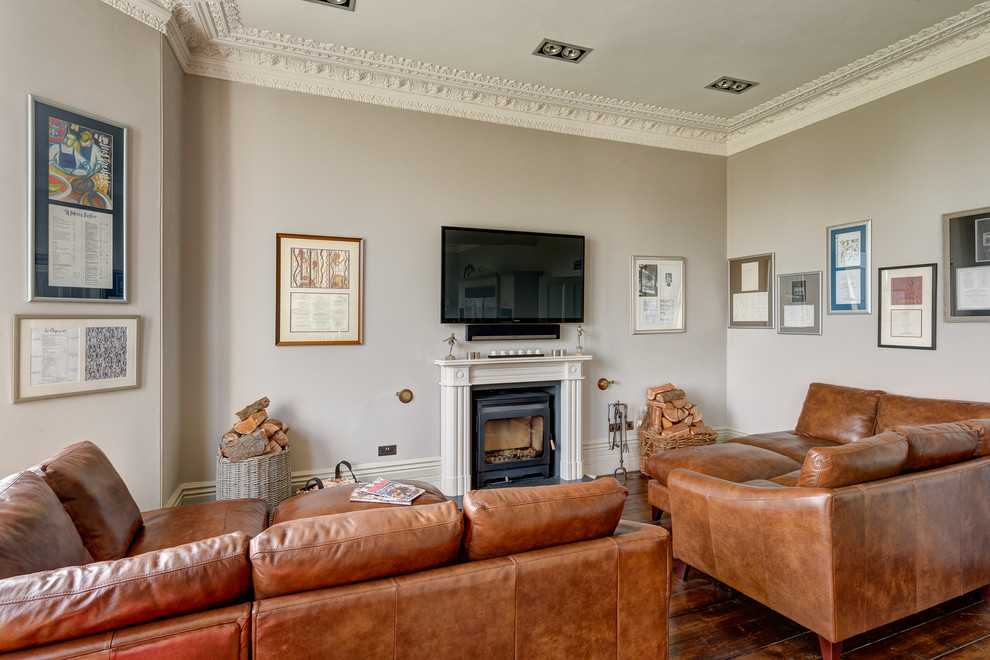 Ejemplo de salón abierto clásico renovado grande con paredes grises, suelo de madera en tonos medios, todas las chimeneas, marco de chimenea de madera y televisor colgado en la pared