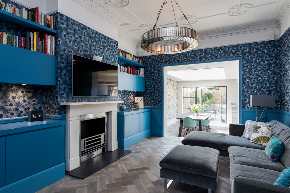 Aménagement d'un salon éclectique de taille moyenne et ouvert avec un mur bleu, parquet foncé, une cheminée standard, un manteau de cheminée en métal, un téléviseur fixé au mur et un sol marron.