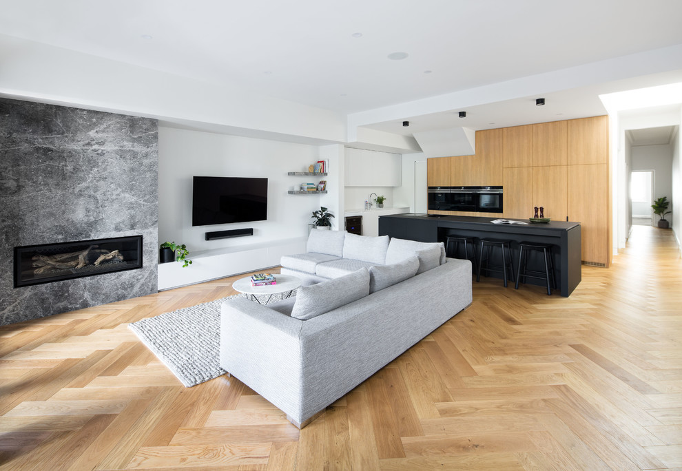 Mid-sized trendy enclosed light wood floor and green floor living room photo in Melbourne with white walls, a corner fireplace, a stone fireplace and a wall-mounted tv