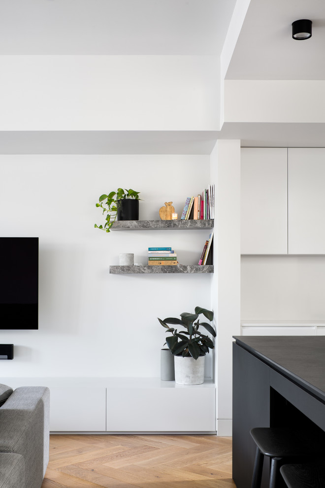 Inredning av ett modernt mellanstort separat vardagsrum, med vita väggar, ljust trägolv, en öppen hörnspis, en spiselkrans i sten, en väggmonterad TV och grönt golv