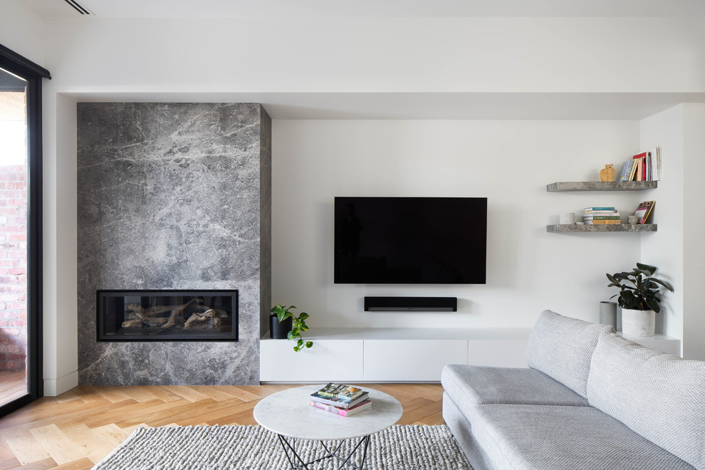 Exempel på ett mellanstort modernt separat vardagsrum, med vita väggar, ljust trägolv, en öppen hörnspis, en spiselkrans i sten, en väggmonterad TV och grönt golv