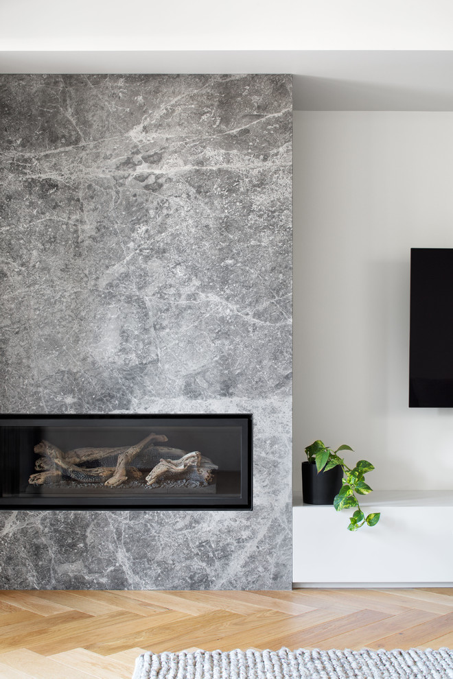 Exempel på ett mellanstort modernt separat vardagsrum, med vita väggar, ljust trägolv, en öppen hörnspis, en spiselkrans i sten, en väggmonterad TV och grönt golv