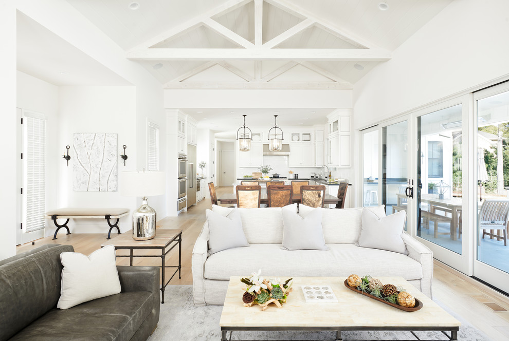Modelo de salón abierto de estilo de casa de campo con paredes blancas, suelo de madera clara y suelo beige