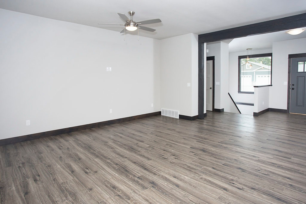 Mittelgroßes, Offenes Uriges Wohnzimmer mit grauer Wandfarbe, Laminat, TV-Wand und buntem Boden in Sonstige