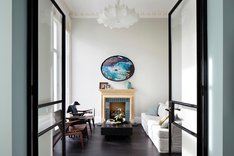 Photo of a contemporary enclosed living room in London with white walls, a standard fireplace and a tiled fireplace surround.