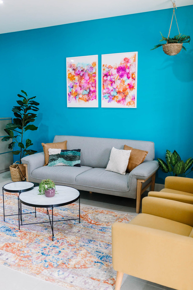 Пример оригинального дизайна: изолированная гостиная комната среднего размера в стиле фьюжн с синими стенами, полом из керамической плитки, телевизором на стене и бежевым полом