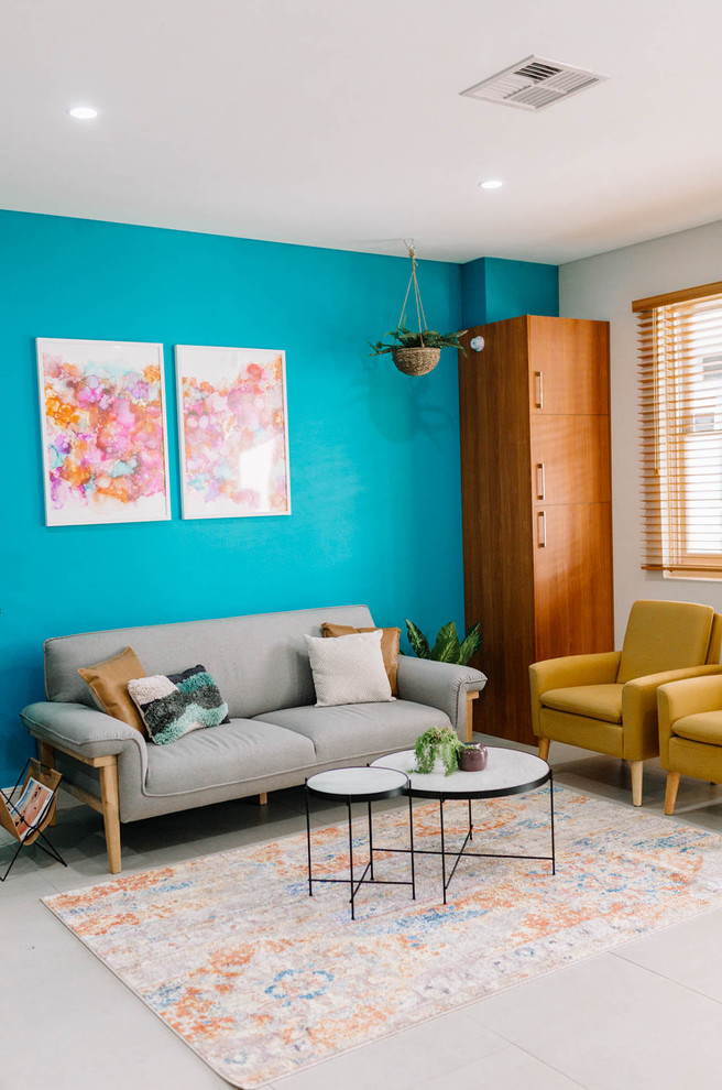 Imagen de salón cerrado bohemio de tamaño medio con paredes azules, suelo de baldosas de cerámica, televisor colgado en la pared y suelo beige