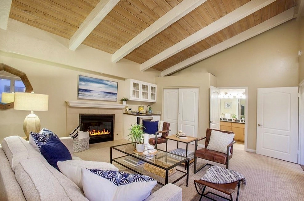This is an example of a medium sized mediterranean open plan living room in San Diego with white walls, terracotta flooring, a stone fireplace surround and brown floors.
