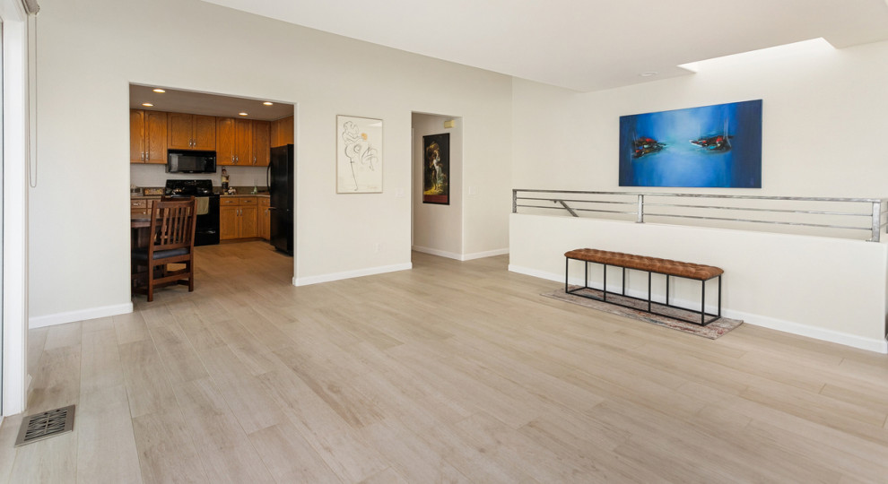 サンディエゴにある高級な広いビーチスタイルのおしゃれなLDK (白い壁、セラミックタイルの床、標準型暖炉、タイルの暖炉まわり、据え置き型テレビ、グレーの床) の写真