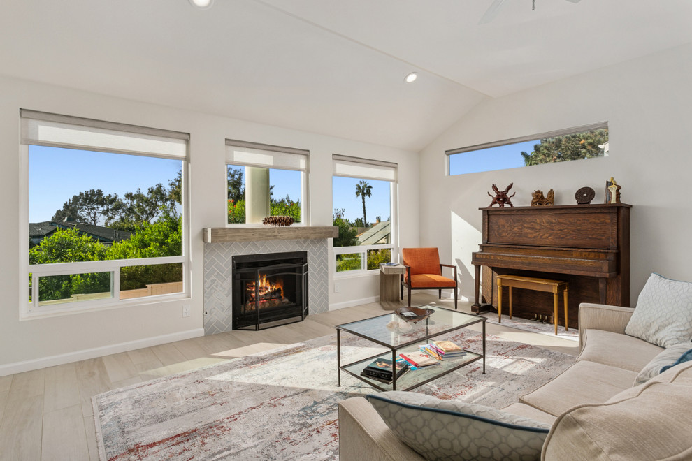 サンディエゴにある高級な広いビーチスタイルのおしゃれなLDK (白い壁、セラミックタイルの床、標準型暖炉、タイルの暖炉まわり、据え置き型テレビ、グレーの床) の写真