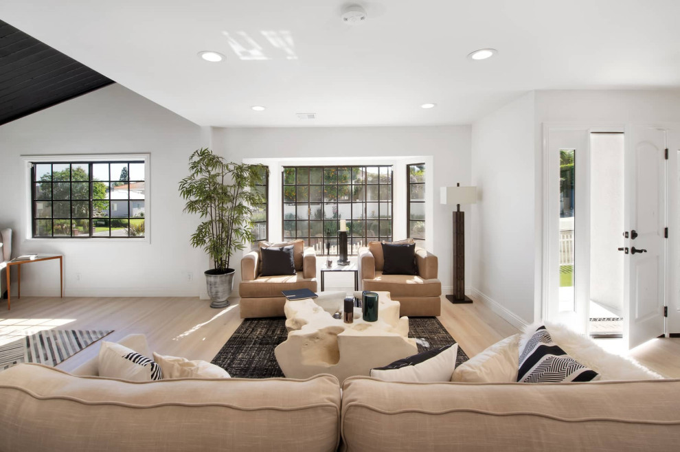 Large retro open plan living room in Los Angeles with white walls and light hardwood flooring.