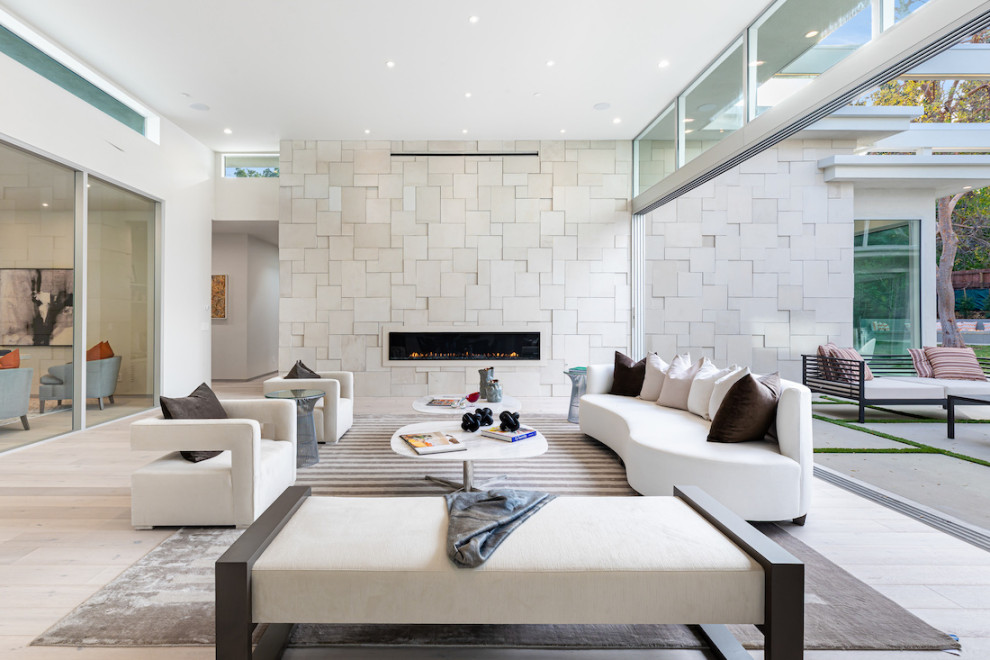 Offenes Modernes Wohnzimmer mit weißer Wandfarbe, hellem Holzboden, Gaskamin, gefliester Kaminumrandung und beigem Boden in Los Angeles