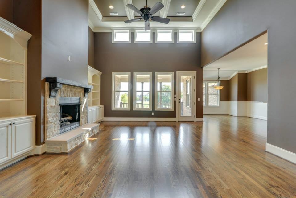 This is an example of a large traditional open plan living room in Nashville with brown walls, dark hardwood flooring, a standard fireplace and a stone fireplace surround.