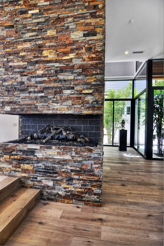Großes, Offenes Modernes Wohnzimmer mit braunem Holzboden, Kaminumrandung aus Stein, Gaskamin und weißer Wandfarbe in Orange County