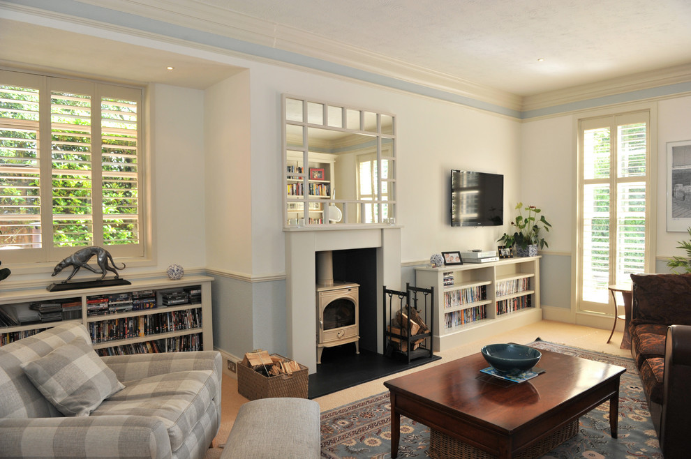 Idee per un soggiorno eclettico con pareti blu, moquette, cornice del camino in legno e TV a parete