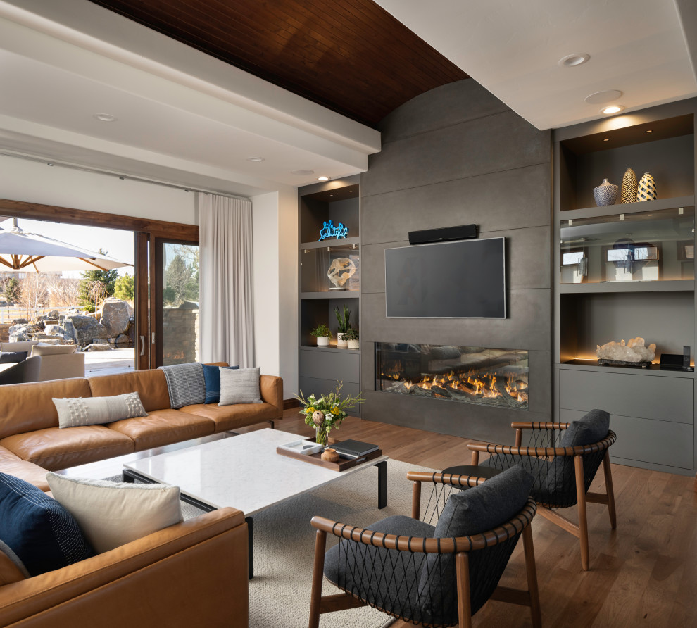 Imagen de salón abierto moderno con suelo de madera en tonos medios, chimenea lineal, marco de chimenea de hormigón, televisor colgado en la pared y madera