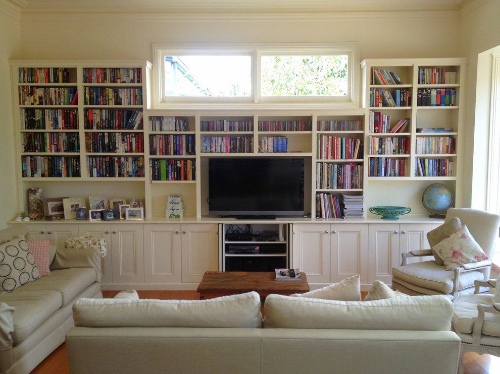 Cette image montre un salon traditionnel de taille moyenne et ouvert avec une bibliothèque ou un coin lecture, un sol en bois brun et un téléviseur indépendant.