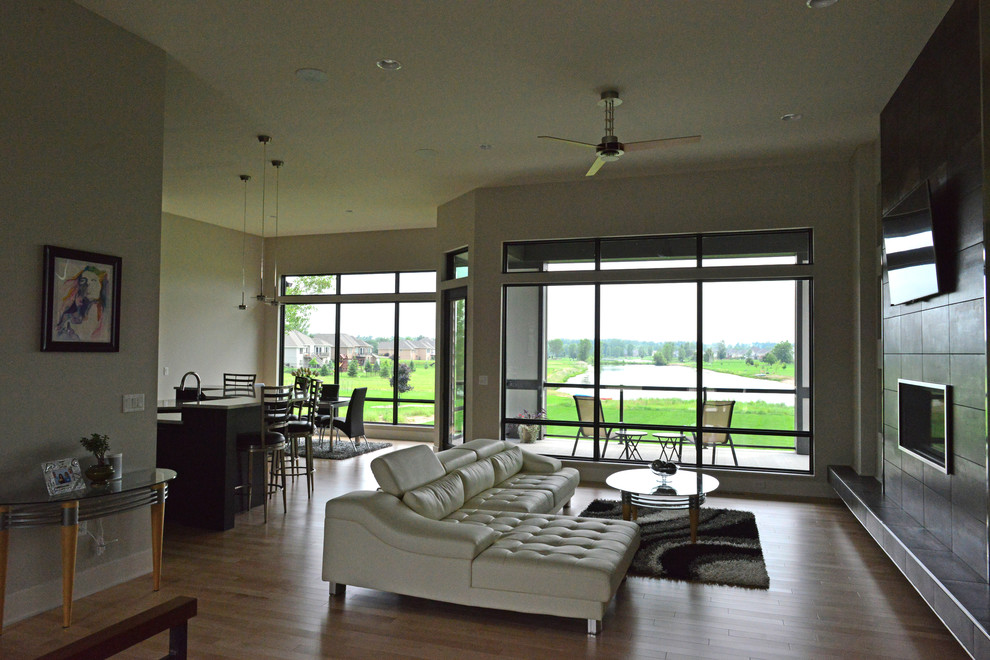 Foto di un grande soggiorno design aperto con pavimento in legno massello medio, camino classico e TV a parete