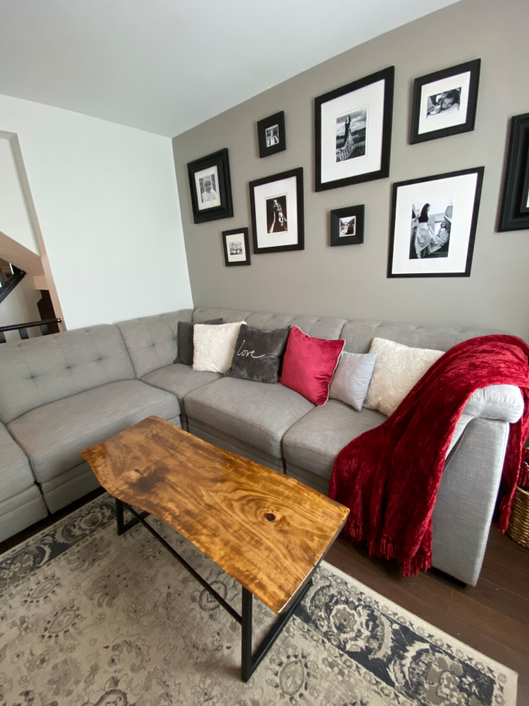 Esempio di un soggiorno moderno di medie dimensioni e aperto con sala formale, pareti grigie, pavimento in laminato, TV a parete e pavimento marrone