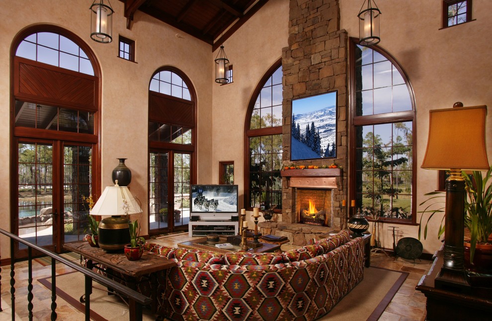 Design ideas for a mediterranean open plan living room in Minneapolis with beige walls, travertine flooring, a stone fireplace surround and a freestanding tv.