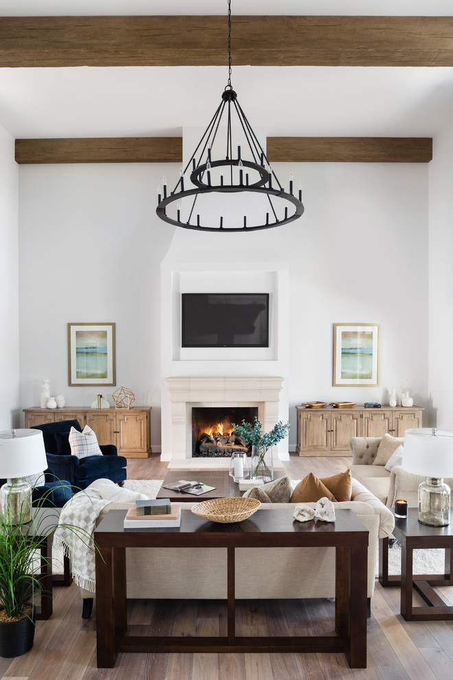 Photo of a country open plan living room in Phoenix with white walls, medium hardwood flooring, a standard fireplace, a wall mounted tv, brown floors and feature lighting.
