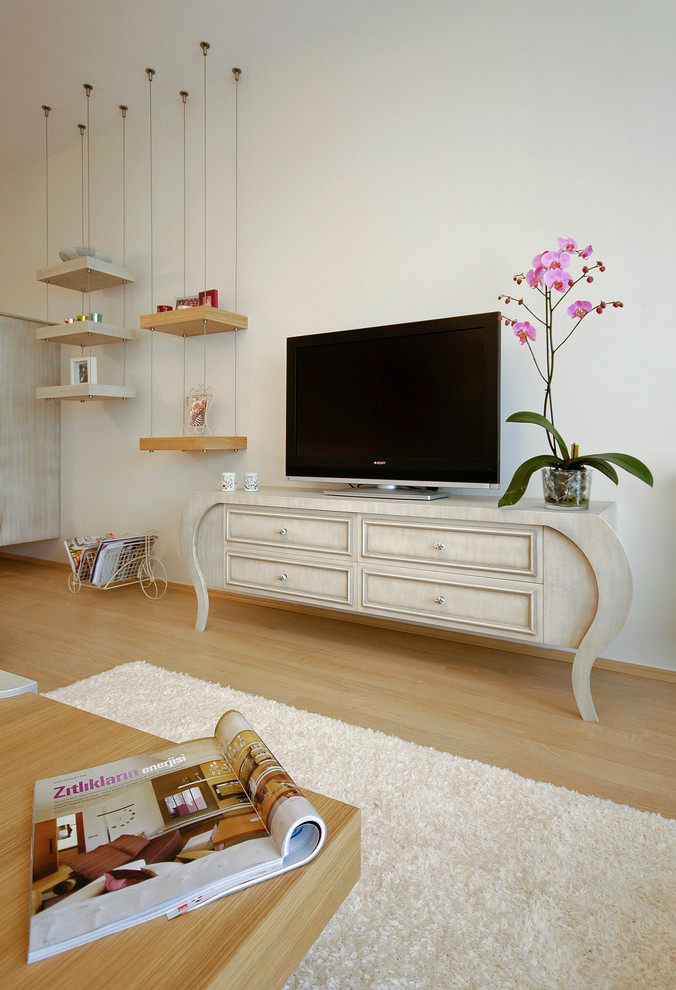 Inredning av ett modernt vardagsrum, med vita väggar, ljust trägolv och en fristående TV