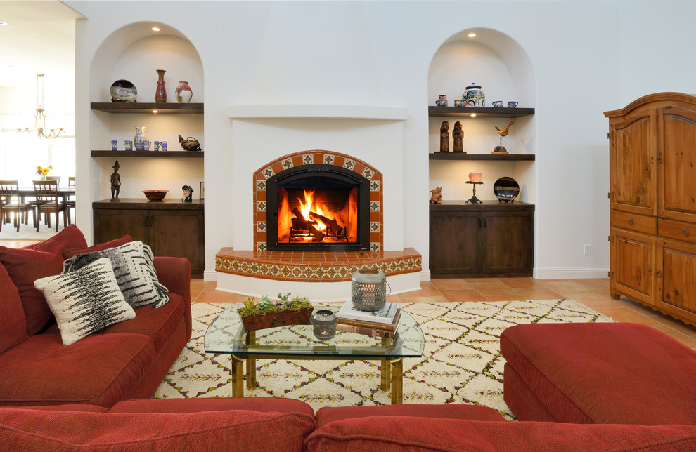 На фото: парадная, открытая гостиная комната в средиземноморском стиле с фасадом камина из плитки, белыми стенами, полом из терракотовой плитки, скрытым телевизором и оранжевым полом