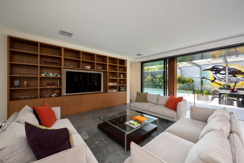 This is an example of a large contemporary open plan living room in Melbourne with limestone flooring and a built-in media unit.