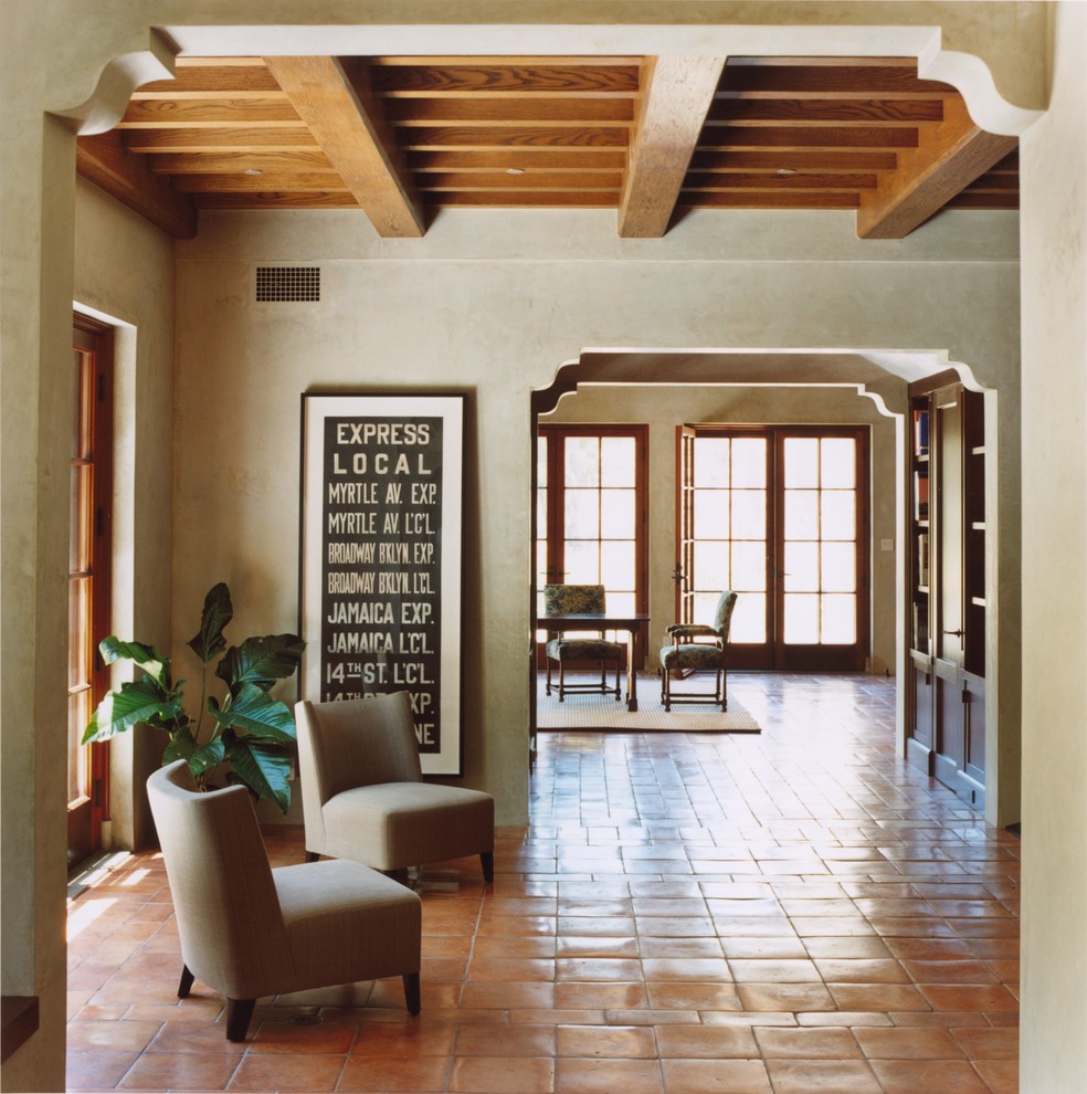 На фото: открытая гостиная комната среднего размера в средиземноморском стиле с серыми стенами и полом из терракотовой плитки без камина с