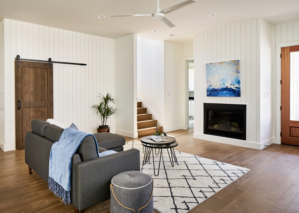 Idee per un soggiorno stile marino con pareti bianche, pavimento in legno massello medio, camino lineare Ribbon e nessuna TV