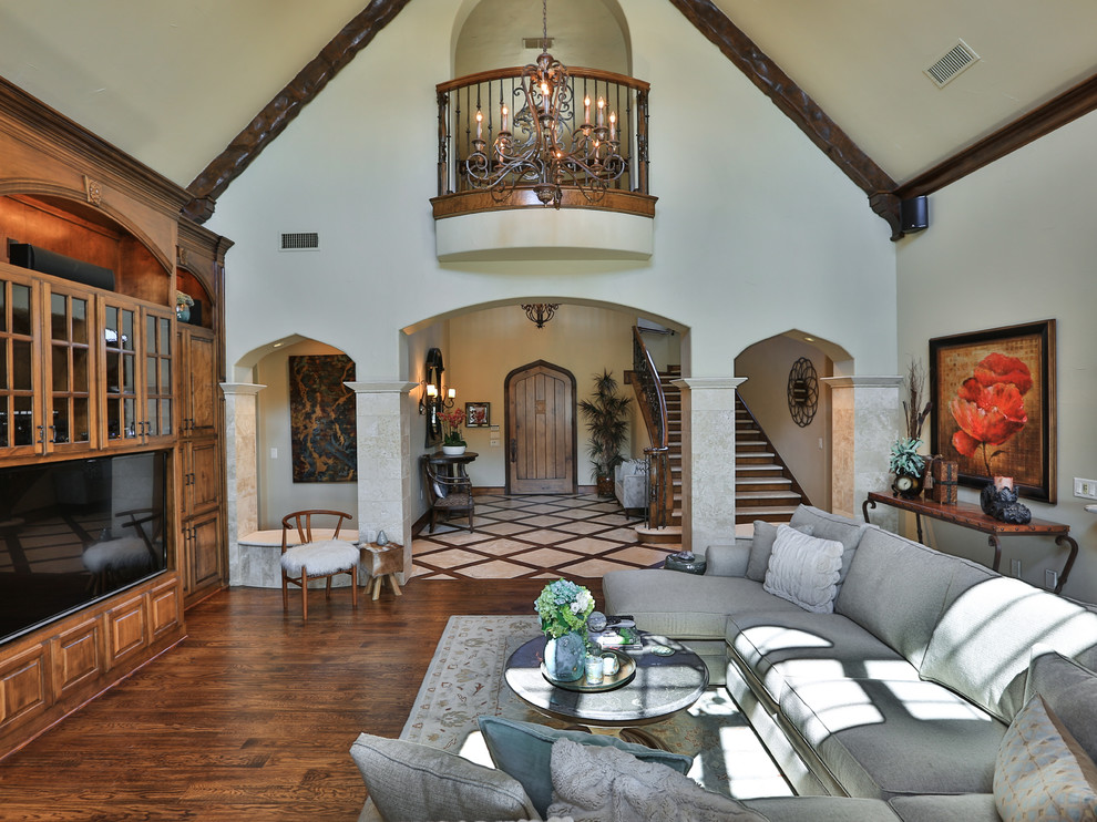 Example of a large tuscan enclosed dark wood floor and brown floor living room design in Dallas with white walls, no fireplace and a media wall