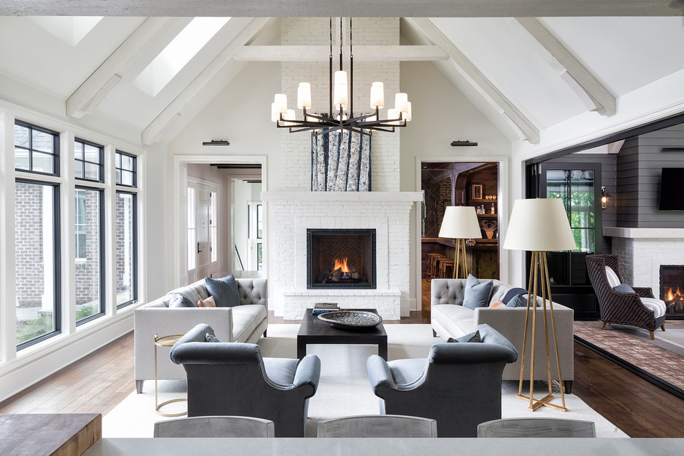Inspiration pour un grand salon traditionnel ouvert avec un mur blanc, une cheminée standard, un manteau de cheminée en brique, un sol marron et un sol en bois brun.