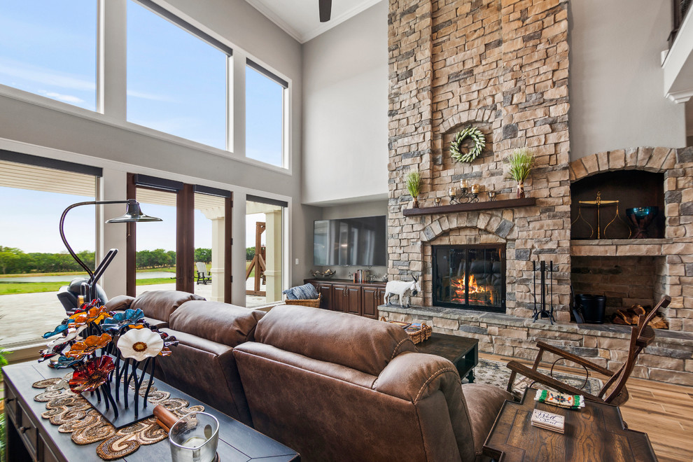 Inspiration for a large country formal and open concept ceramic tile and brown floor living room remodel in Kansas City with gray walls, a standard fireplace, a stone fireplace and a media wall