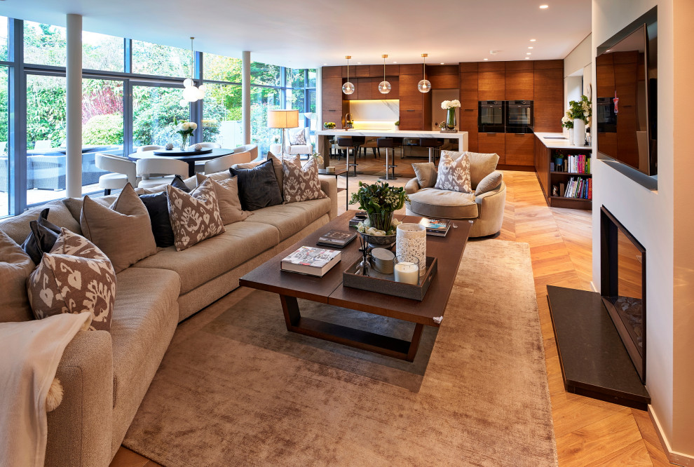 Modernes Wohnzimmer mit beiger Wandfarbe, braunem Holzboden, Kamin und braunem Boden in Sonstige