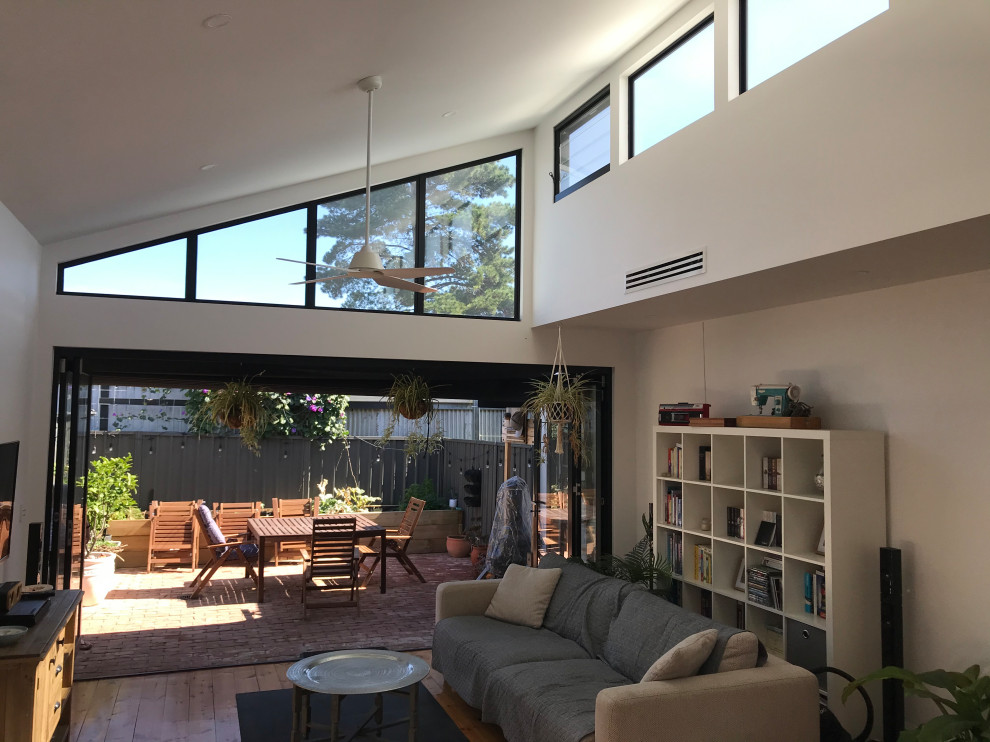 Kleines, Offenes Modernes Wohnzimmer ohne Kamin mit weißer Wandfarbe, gebeiztem Holzboden, freistehendem TV und gewölbter Decke in Adelaide